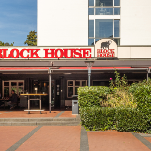 Außenansicht des BLOCK HOUSE Frankfurt Westend mit Terrasse, Eingang zum Steakhouse und Gästen im Außenbereich
