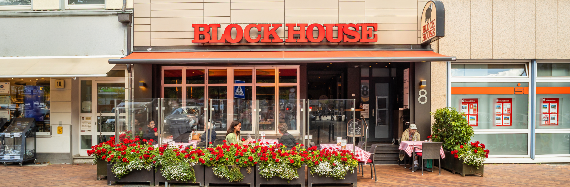 Außenansicht des BLOCK HOUSE Steakhouse in Hamburg Harburg mit Terrasse und Gästen im Außenbereich