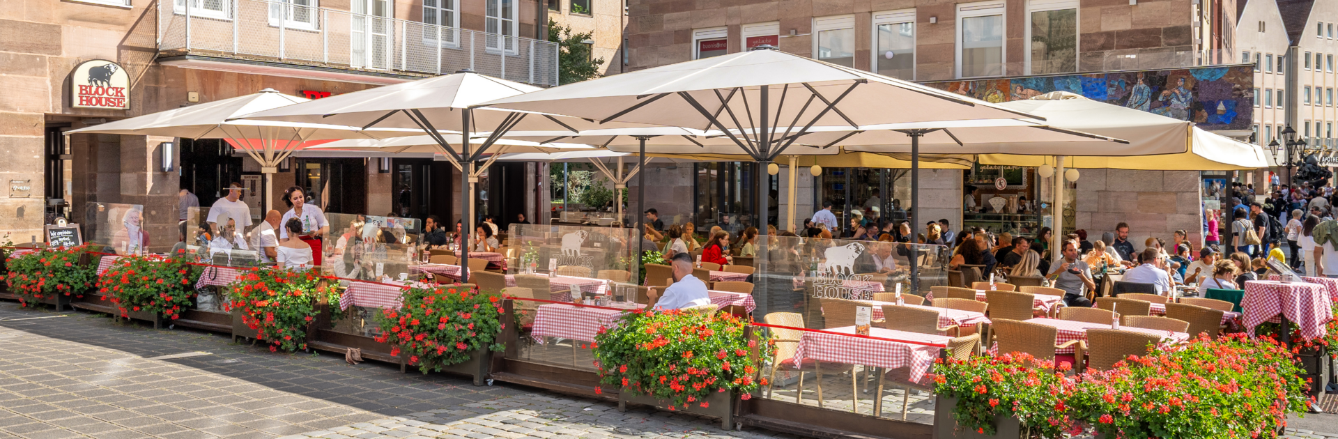 Speisende Gäste auf der sonnengeschützten Terrasse des BLOCK HOUSE Restaurants in Nürnberg