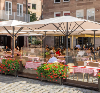 Speisende Gäste auf der sonnengeschützten Terrasse des BLOCK HOUSE Restaurants in Nürnberg