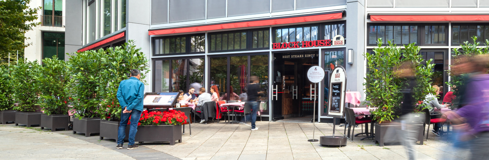 Außenansicht des BLOCK HOUSE Stuttgart Königstraße mit Terrasse und Gästen vor dem Restaurant.