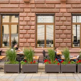 Außenansicht des BLOCK HOUSE Frankfurt am Börsenplatz mit Terrasse, begrüntem Außenbereich und Gästen vor dem Restaurant.