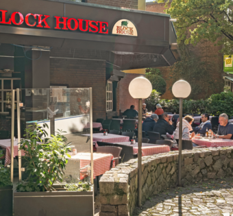 BLOCK HOUSE Hamburg Volksdorf mit Gästen vor dem Steakhouse und Sitzplätzen auf der Terrasse unter großen Bäumen