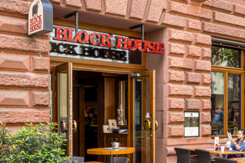 Terrasse des BLOCK HOUSE Frankfurt am Börsenplatz mit Außensitzplätzen und begrüntem Eingangsbereich vor der historischen Fassade.