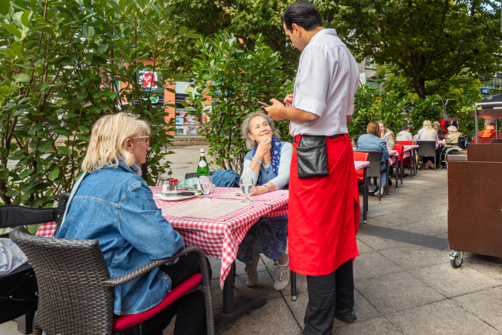Servicekraft betreut Gäste auf der Terrasse des BLOCK HOUSE Stuttgart Königstraße.