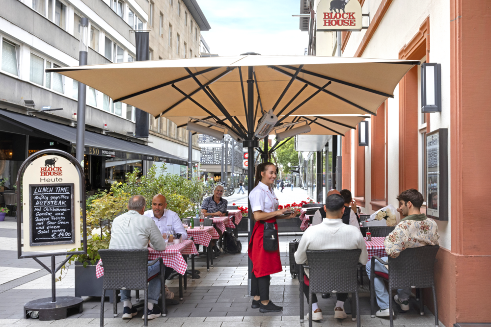 Terrasse des BLOCK HOUSE Mannheim mit Gästen und Servicekraft im Außenbereich.