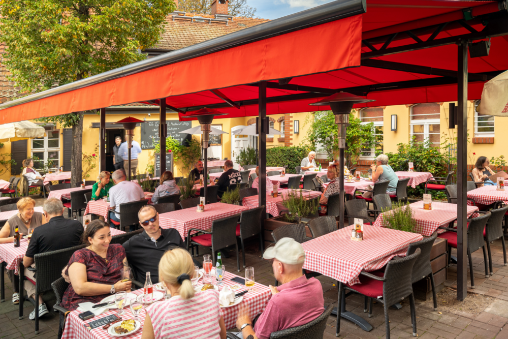 Terrasse des BLOCK HOUSE Restaurants Zehlendorf in Berlin. Gedeckte Tische mit rot-karierten Tischdecken
