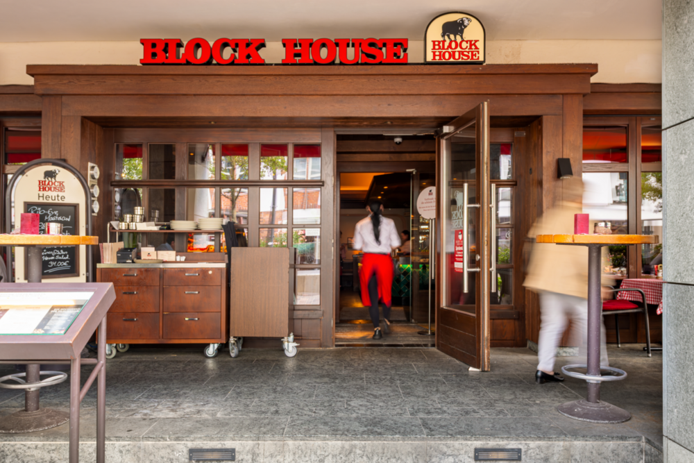 Eingangsbereich des BLOCK HOUSE Rostock mit geöffneten Türen und Gästen im Eingangsbereich.