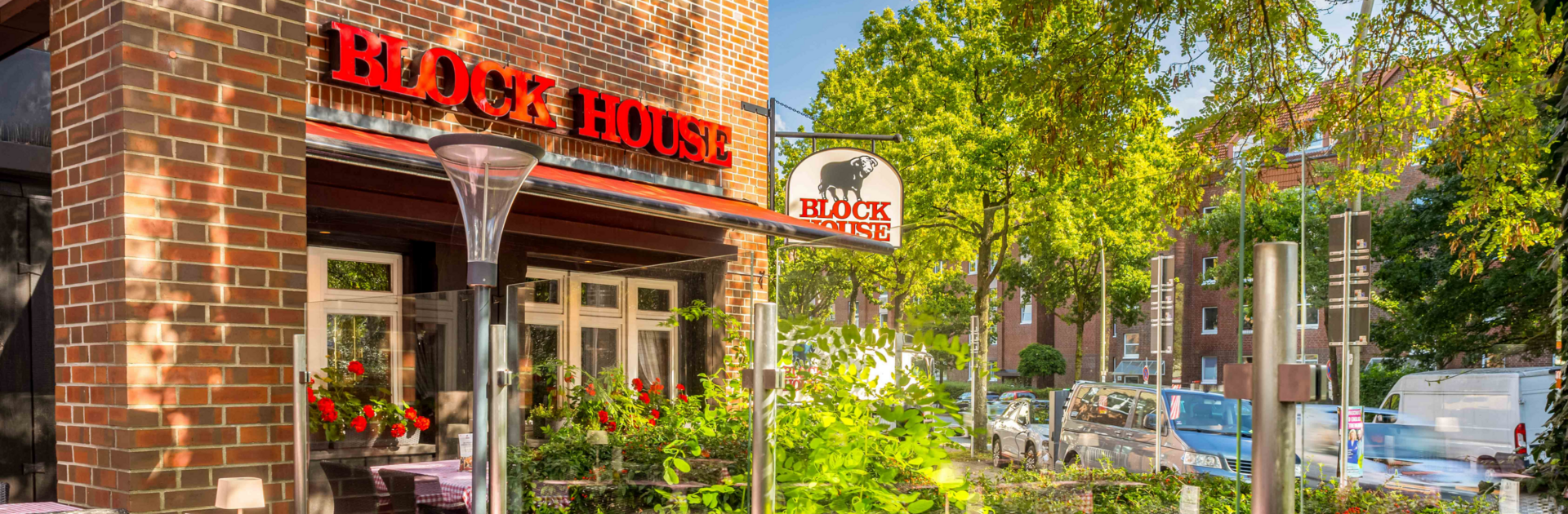 Terrasse vor dem BLOCK HOUSE Hamburg Eidelstedt mit Tischen und rot-weiß karierten Tischdecken vor dem Steakhouse
